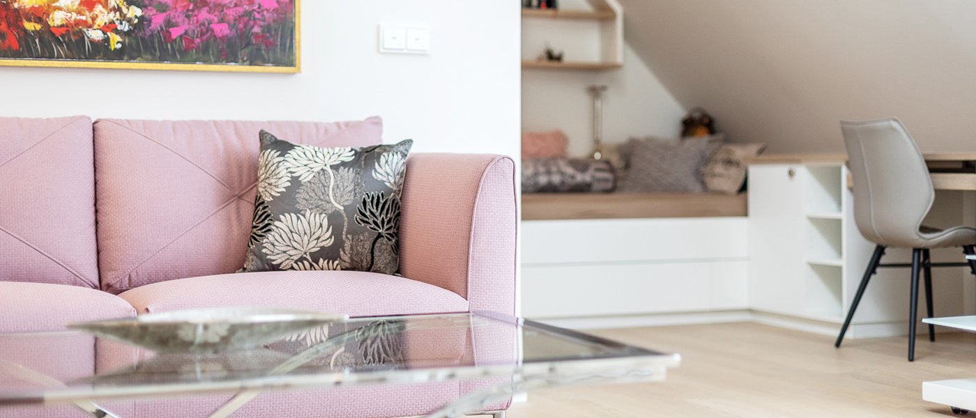 Apartment Zu sehen ist ein Sofa im Vordergrund und ein Bett sowie ein Arbeitsplatz im Hintergrund